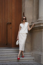a lady in a white vest and a white dress with hollow patterns